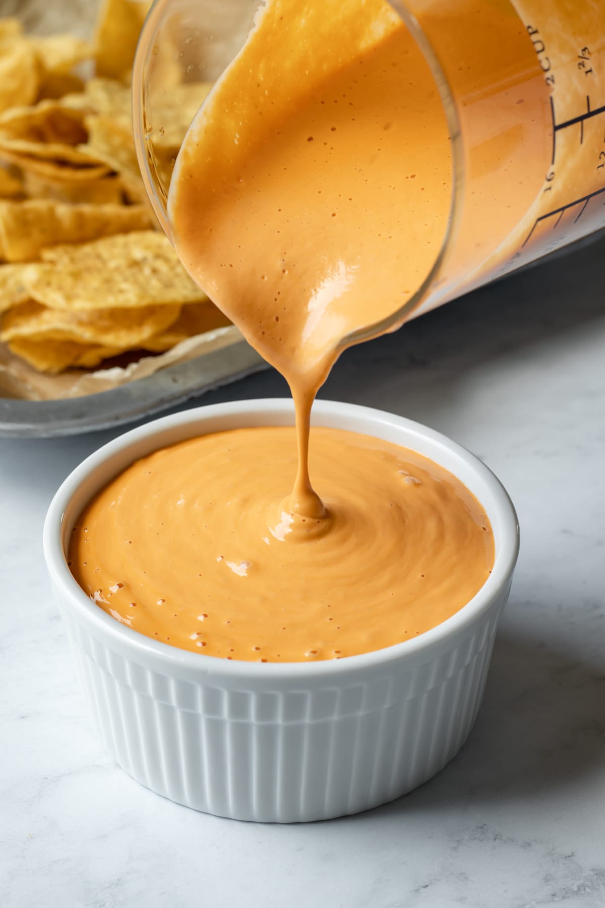 pouring dairy free cheese sauce to show the thick and creamy consistency.