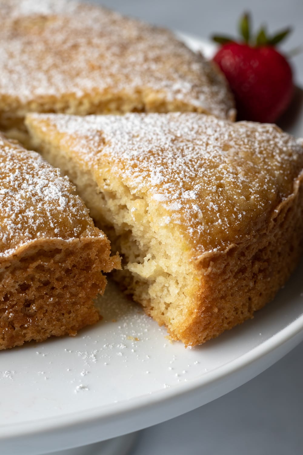 close up of a slice of eggless yogurt cake sprinkled with powdered sugar.