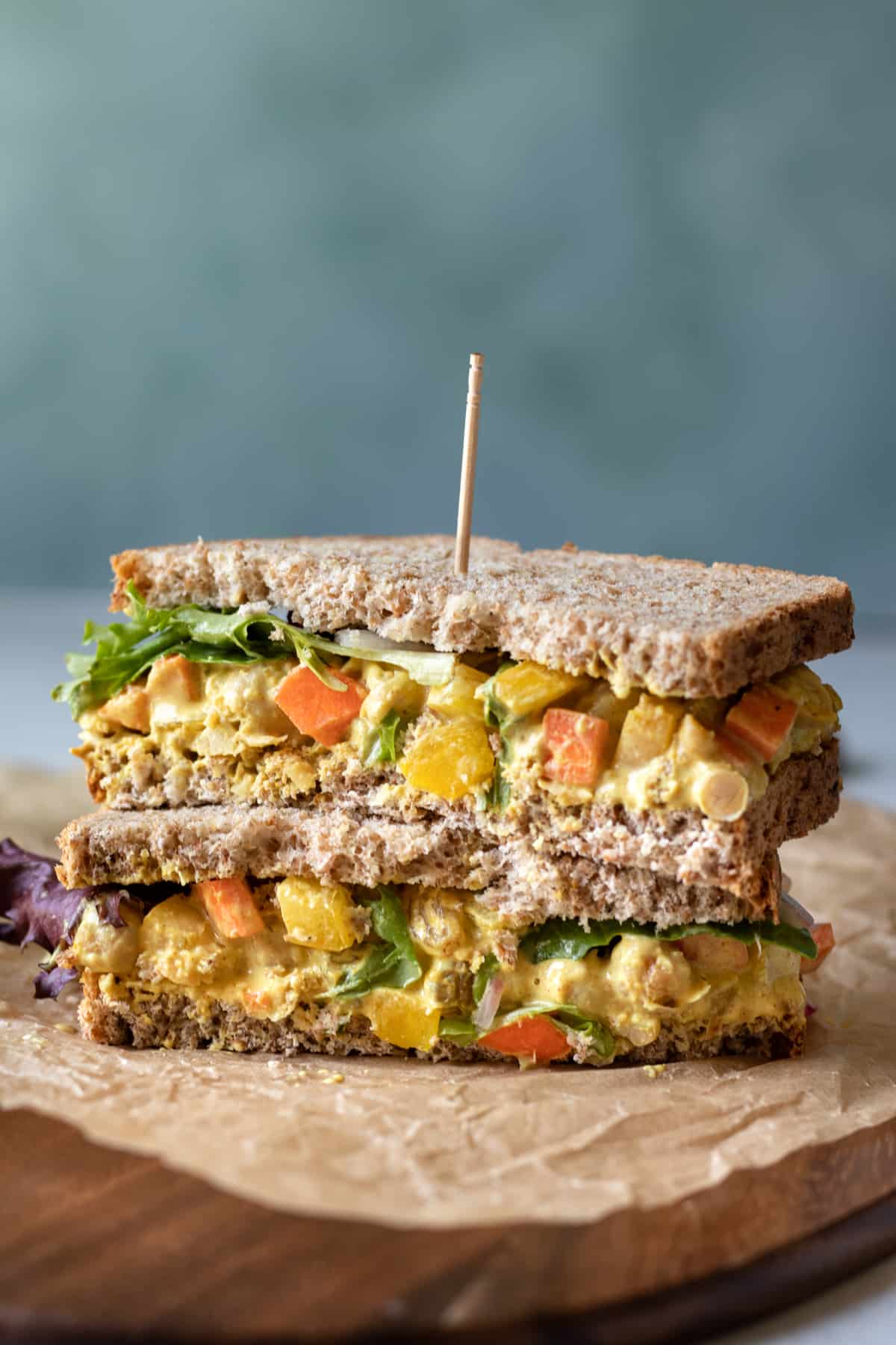 sliced sandwich halves stacked, showing creamy curried filling with carrot and yellow pepper. 