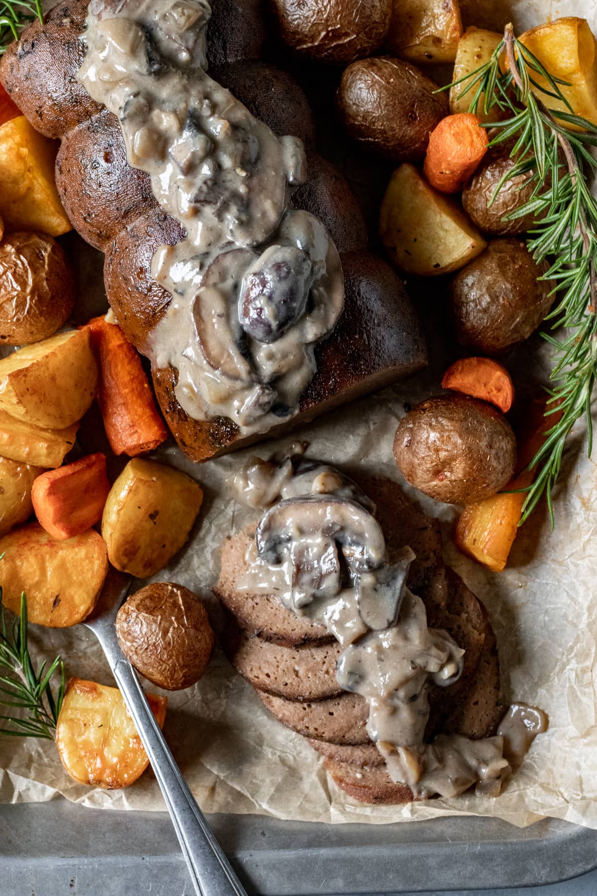 roasted vegetables and sprigs of rosemary surrounding the roast on a platter.