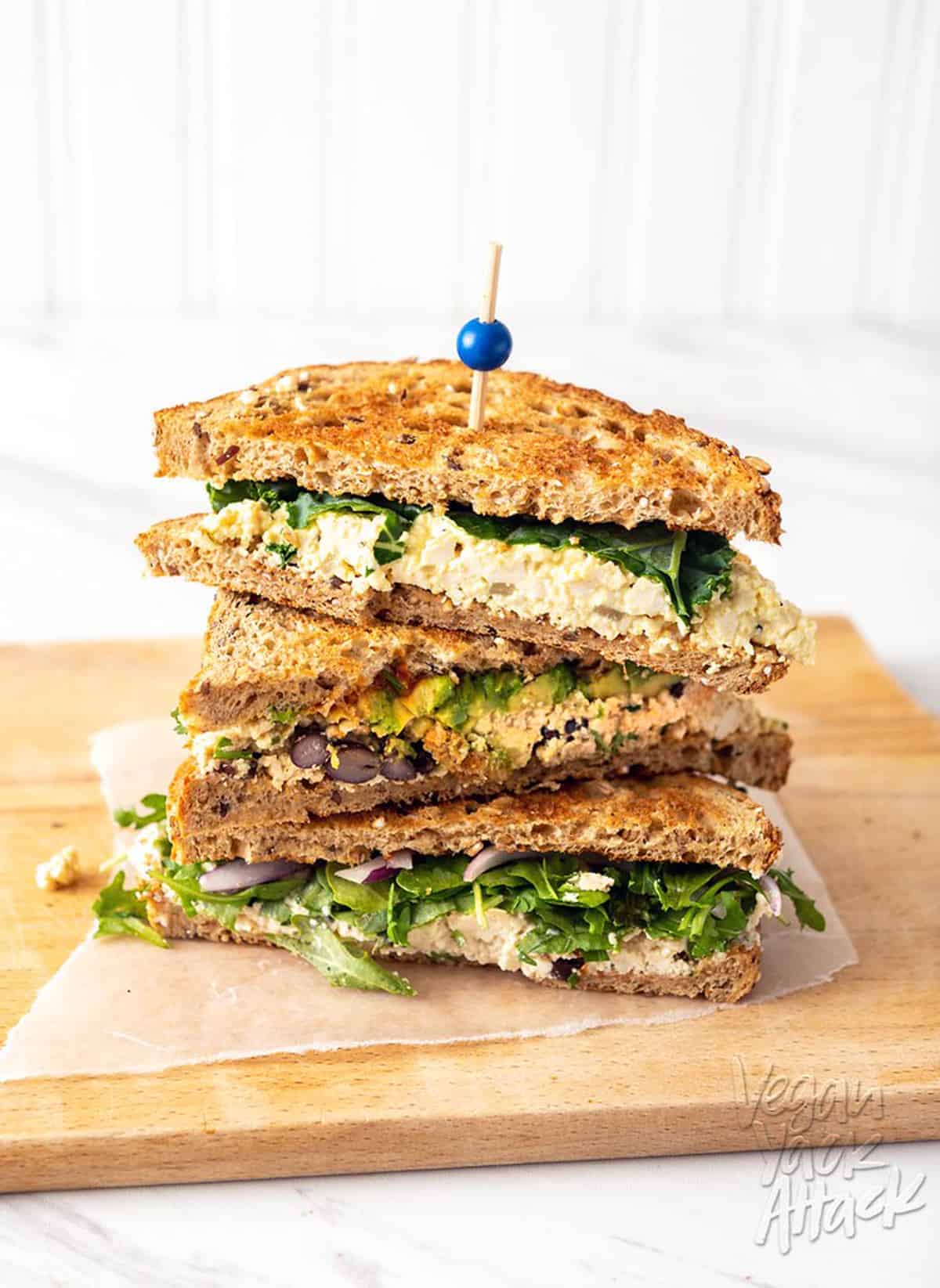 three sandwich halves stacked on a cutting board.