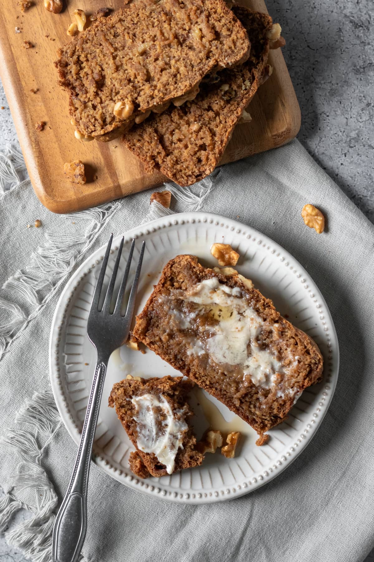 a slice of oat flour banana bread on a plate spread with melting vegan butter.