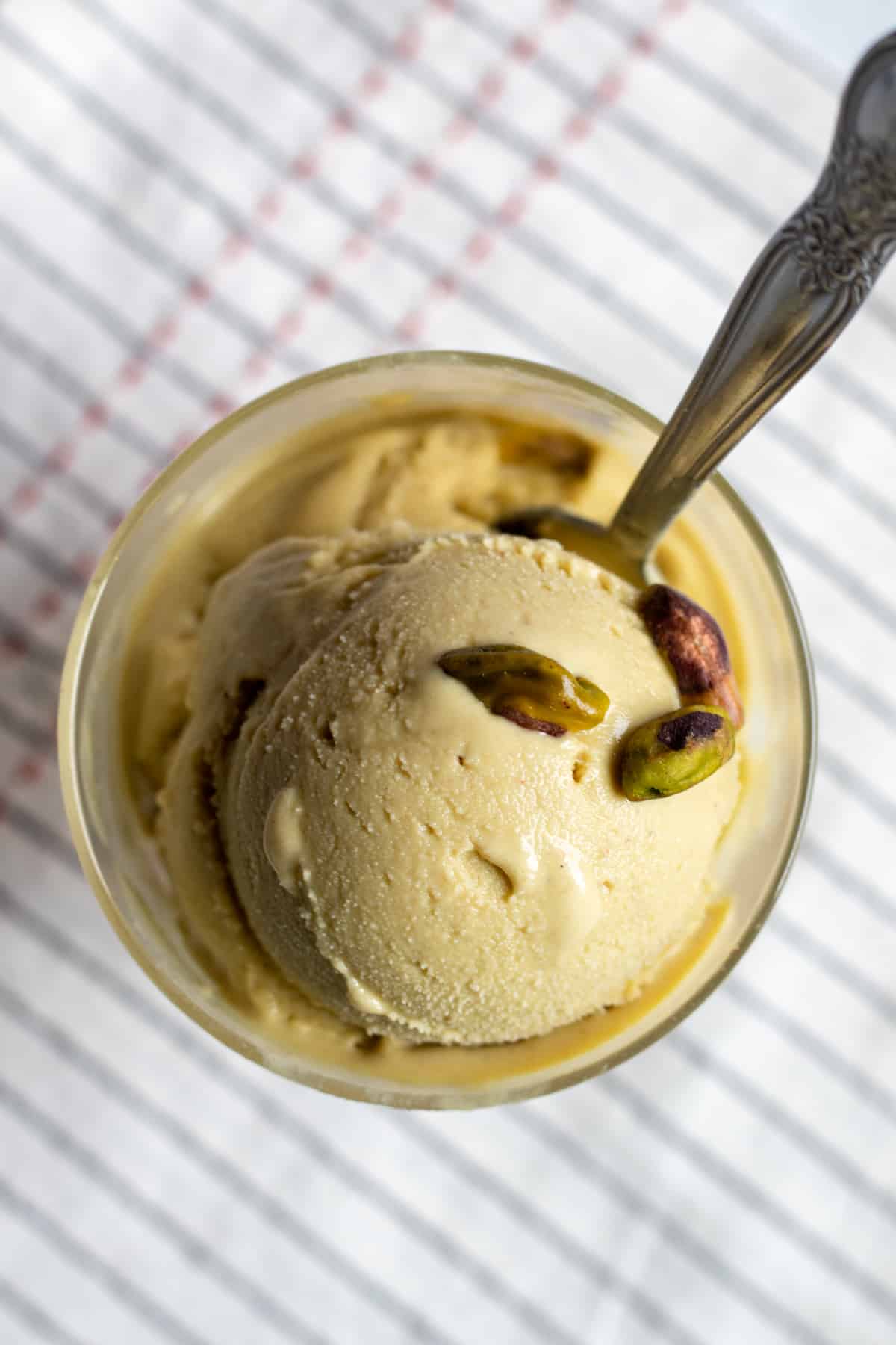 looking down onto a creamy scoop of ice cream with a few pistachios on top.