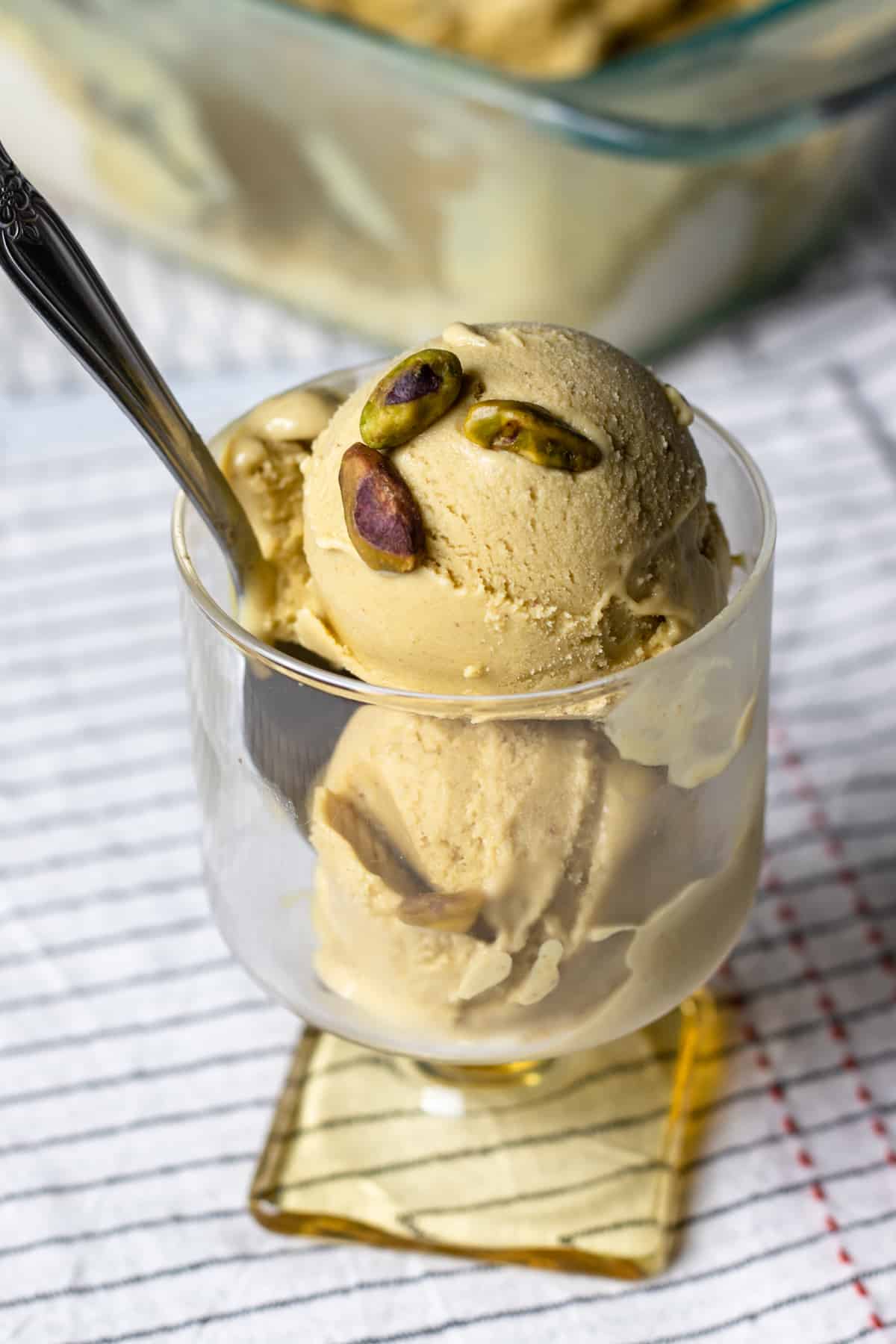 two scoops of vegan ice cream topped with a few pistachios.