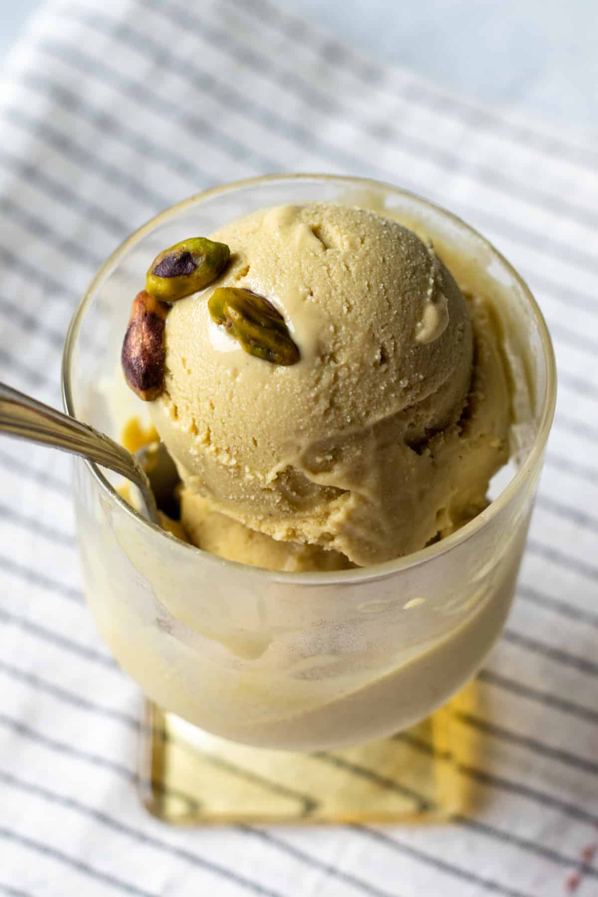 two scoops of vegan pistachio ice cream in a glass.