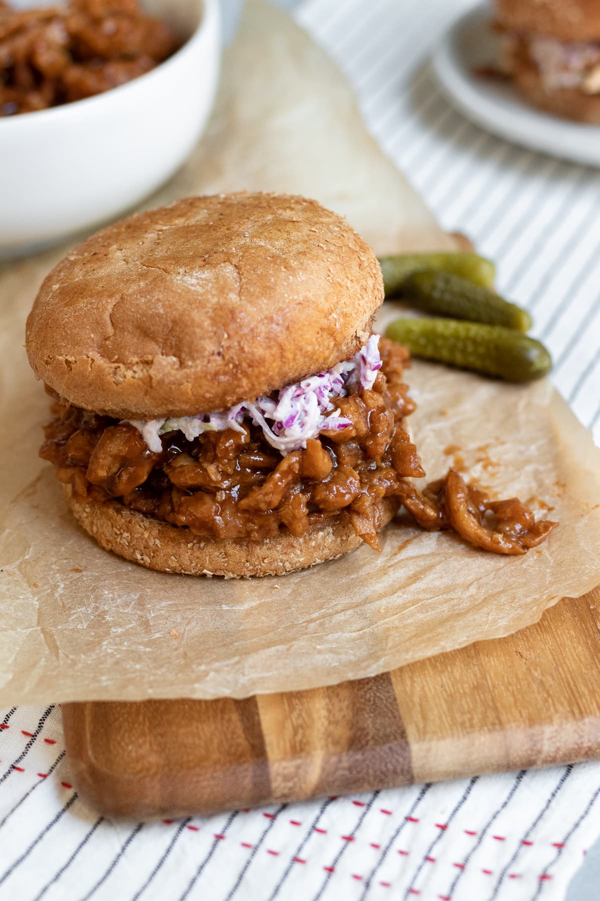 soy curl sandwich on a board with a bowl and plate in background.