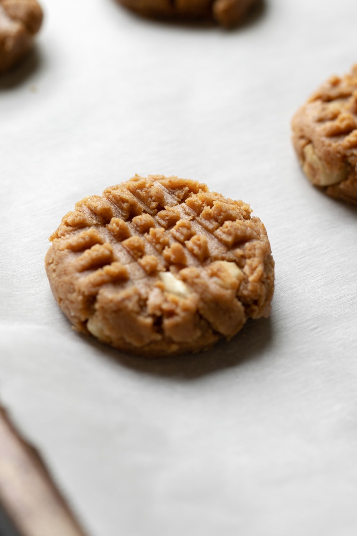 A criss cross pattern created with a fork on top of unbaked cashew cookie dough.