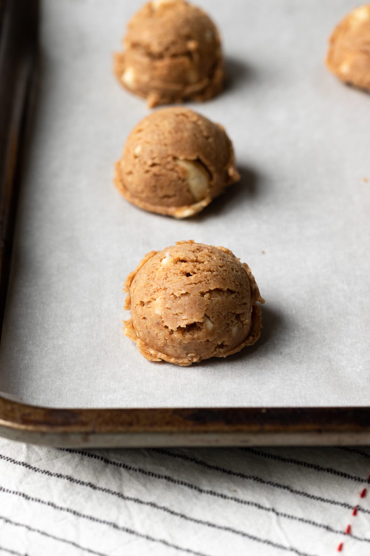 balls of cookie dough lined up on a baking sheet.