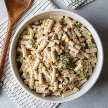 overhead of creamy vegan ranch pasta with herbs, broccoli, and sweet corn