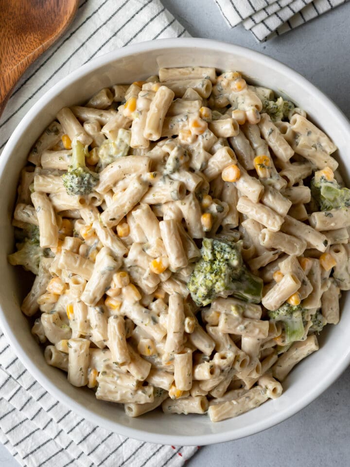 overhead of creamy vegan ranch pasta with herbs, broccoli, and sweet corn