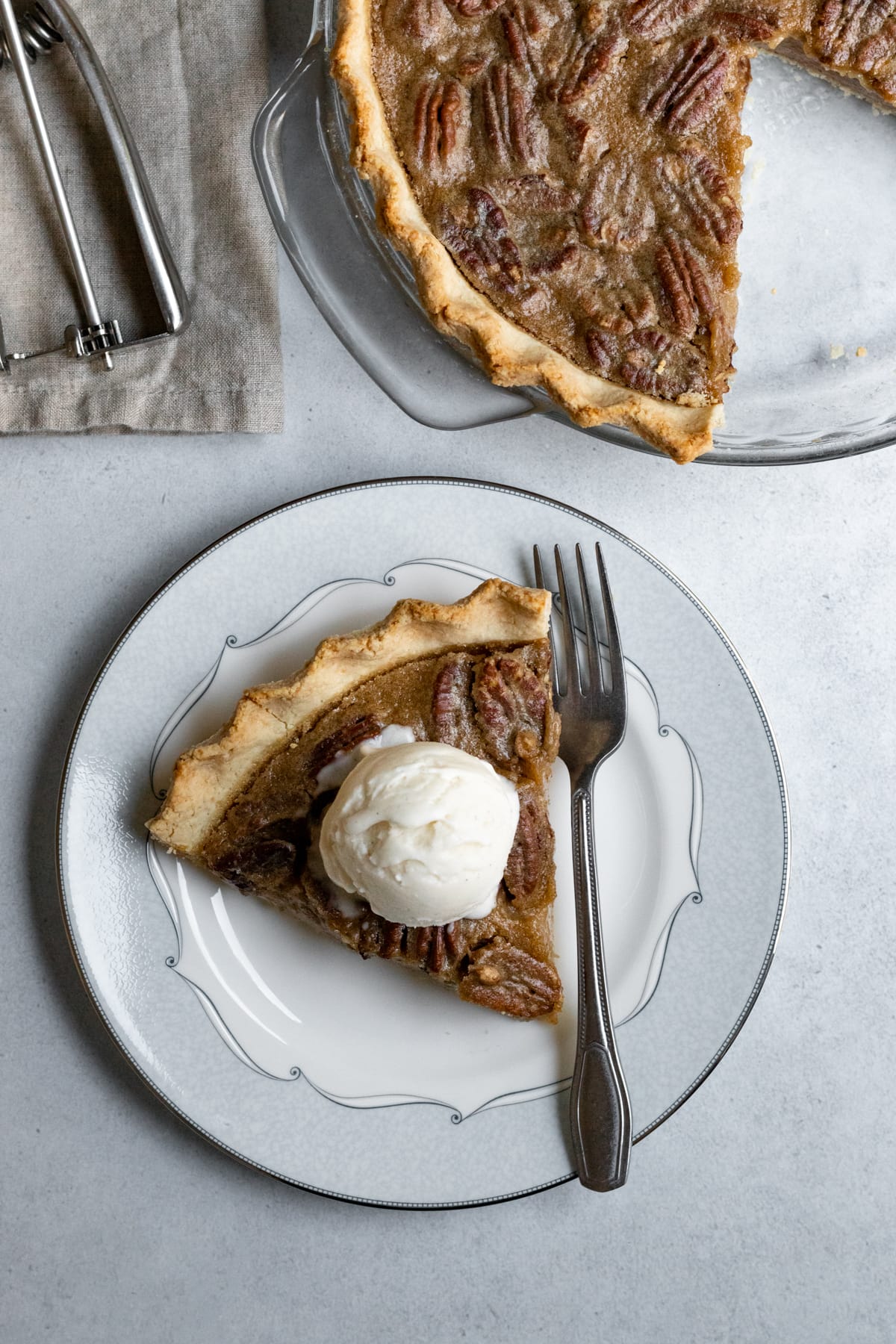 overhead of a slice of pie on a plate topped with a scoop of vegan ice cream.