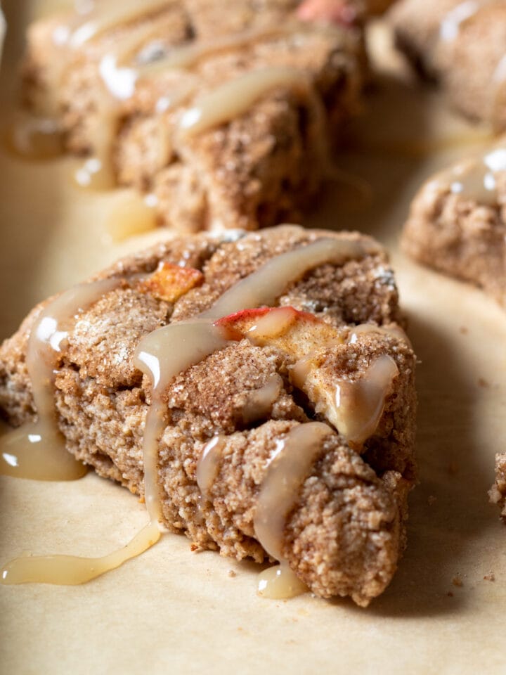 apple cinnamon scones drizzled with maple glaze on a baking pan
