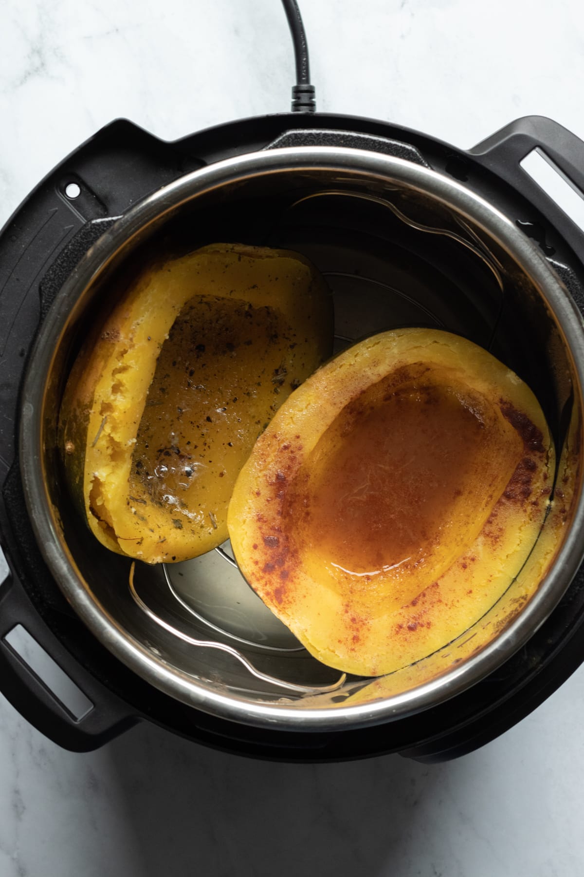 looking into Instant Pot at cooked squash halves.