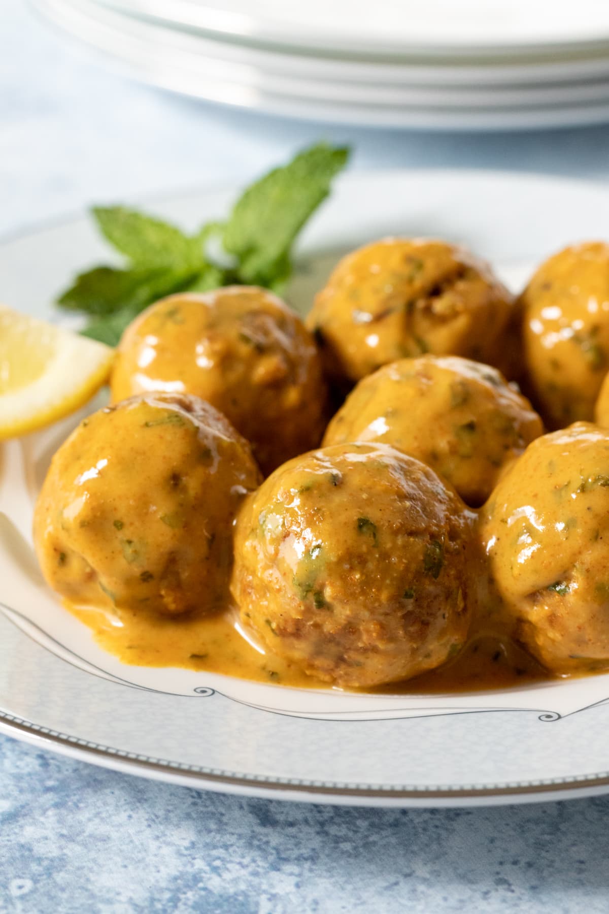 tempeh meatballs covered in creamy tandoori sauce on a white plate.