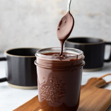 drizzling chocolate sauce from a spoon over a jar full
