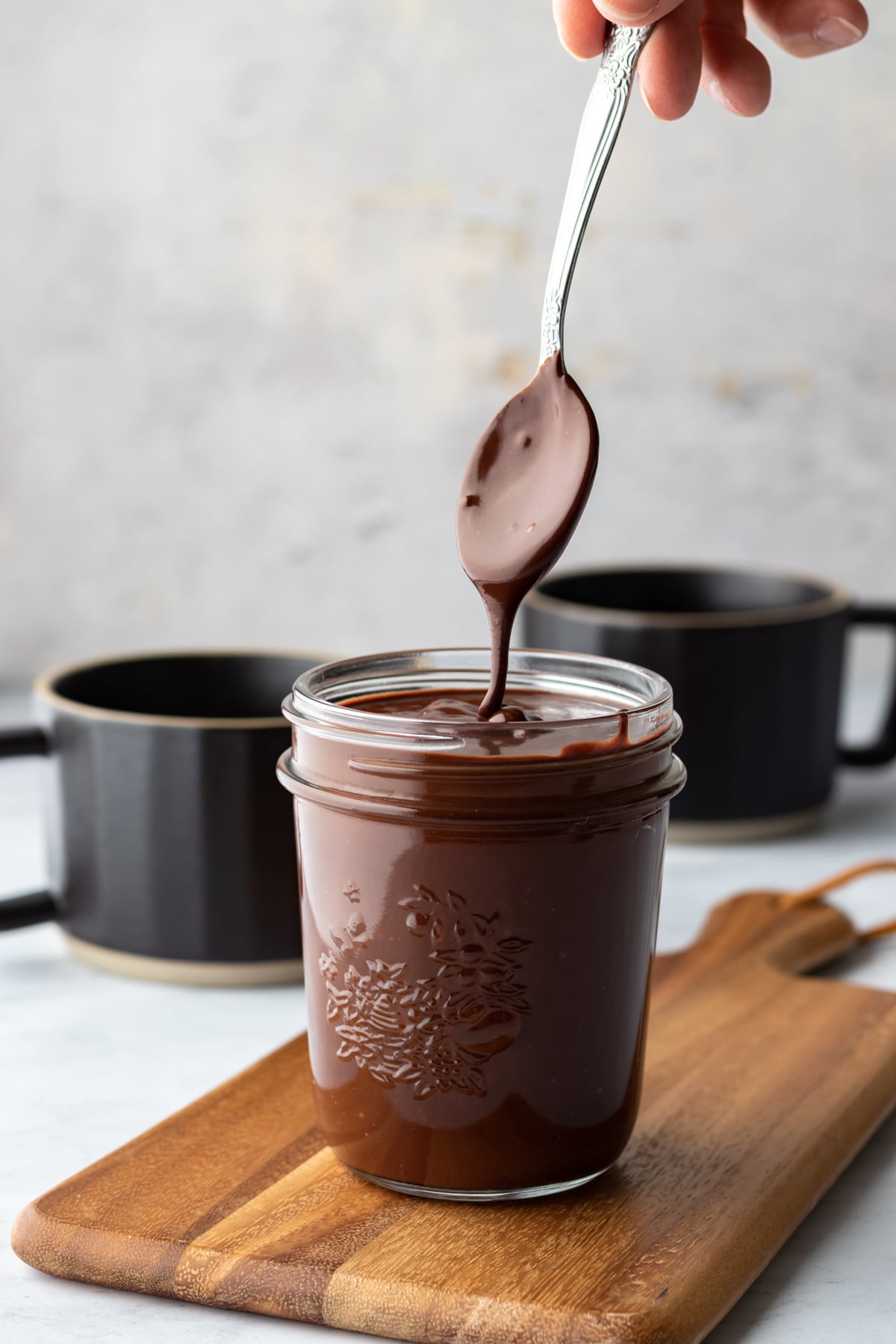 drizzling chocolate sauce from a spoon over a jar full.