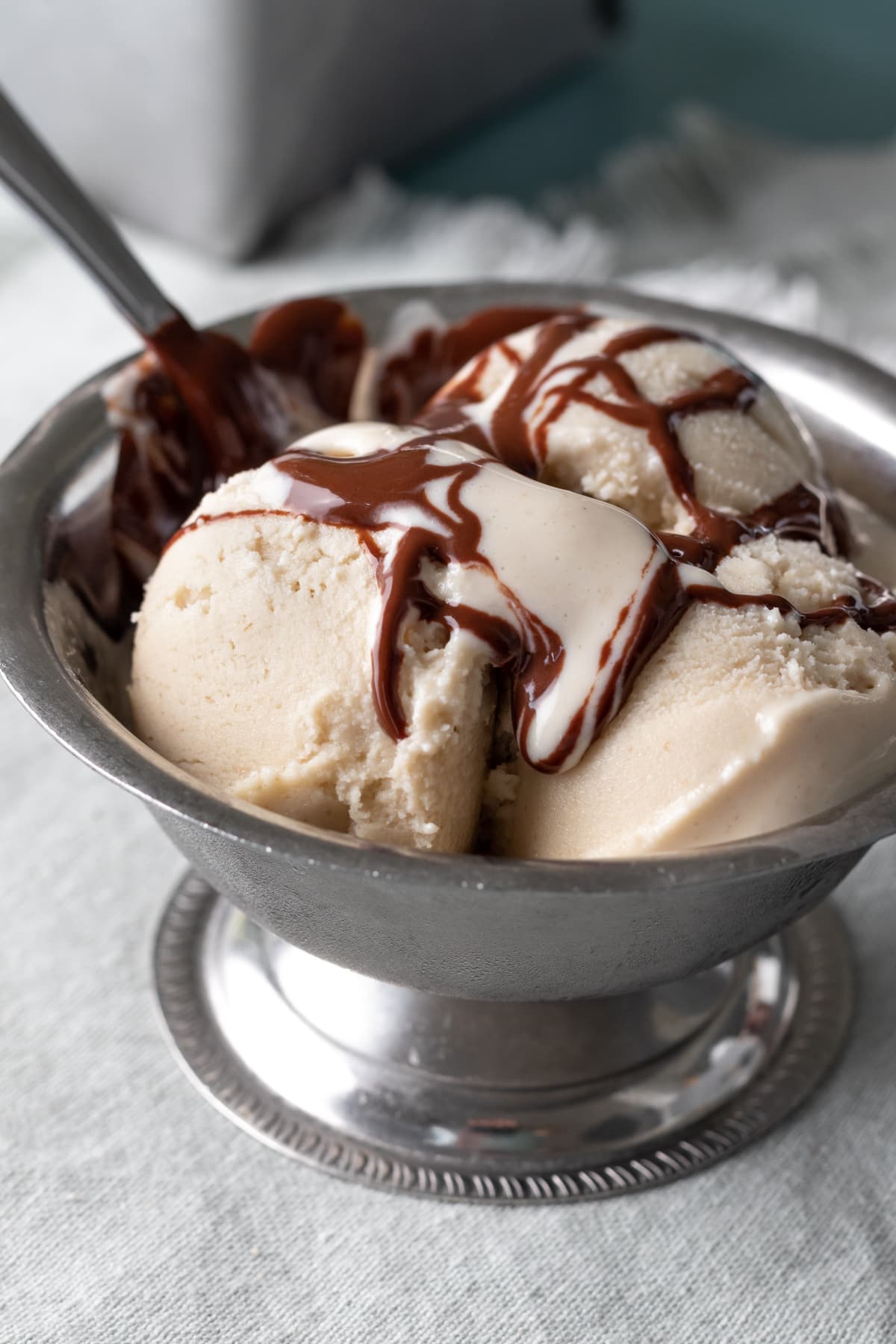 chocolate syrup drizzled on vanilla ice cream in a bowl.