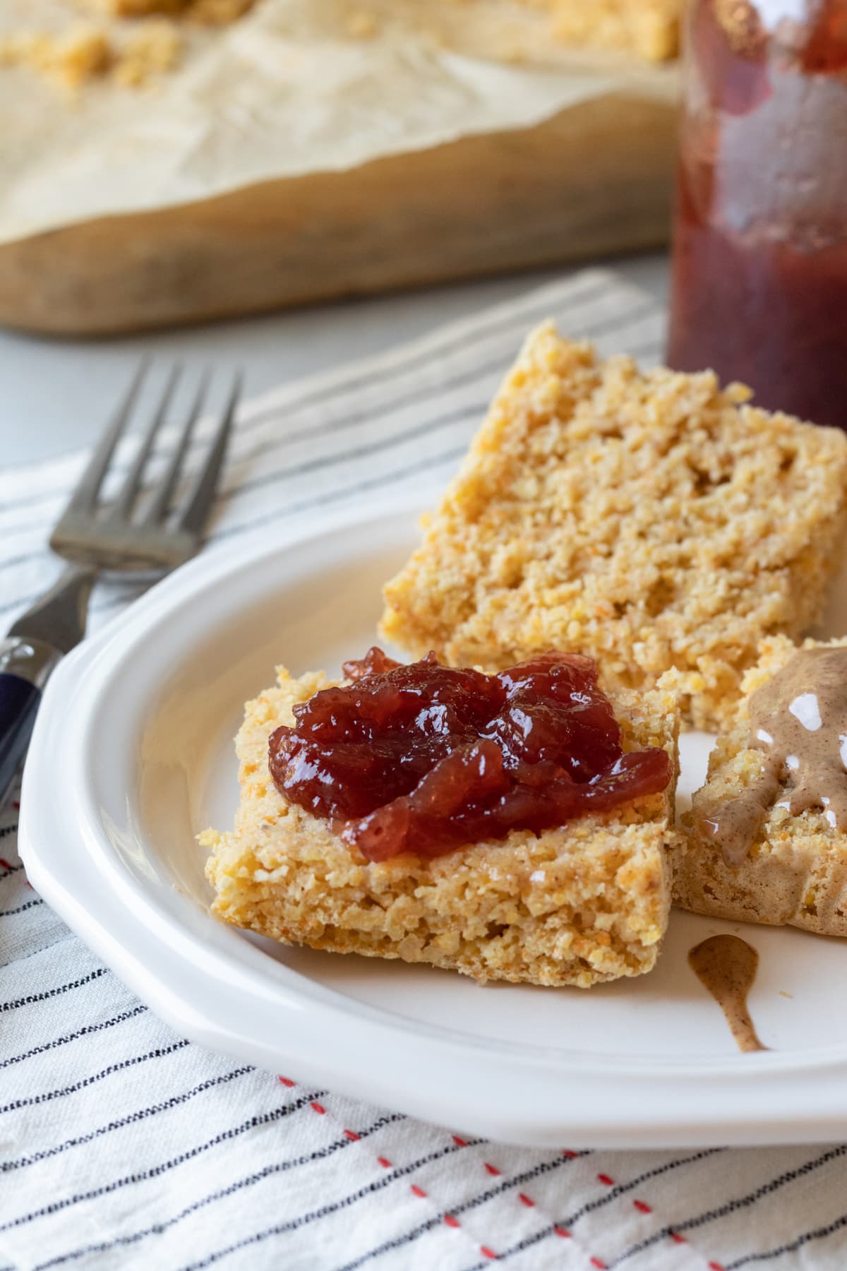 open face cornbread on a plate topped with strawberry jelly