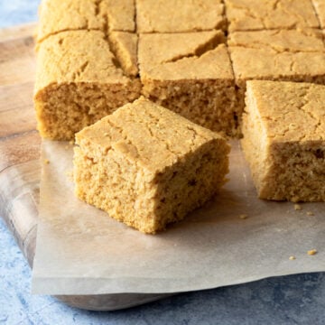 close up of a piece of cornbread with rest of batch in background