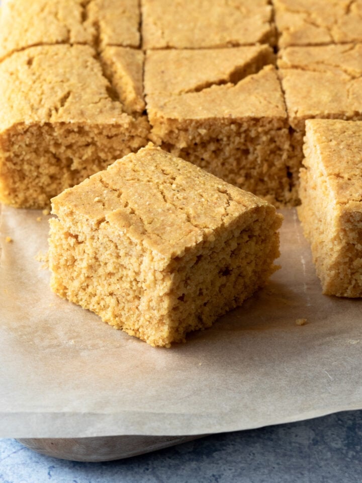 close up of a piece of cornbread with rest of batch in background