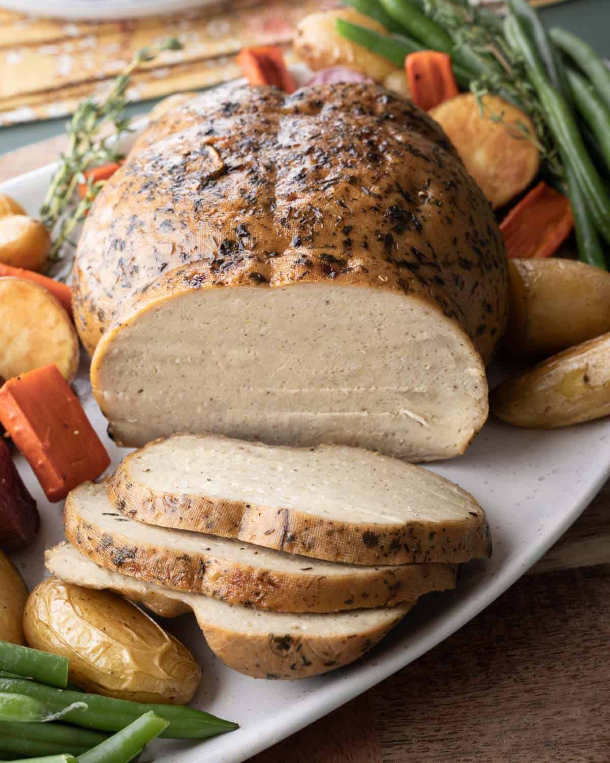 Side view of the sliced seitan turkey on a platter.