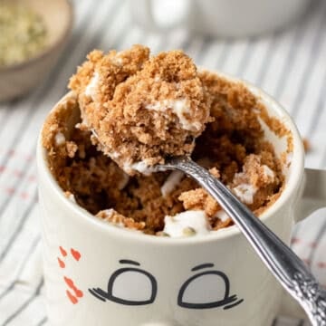 close up of oat flour vegan mug cake in a cute smily face mug.