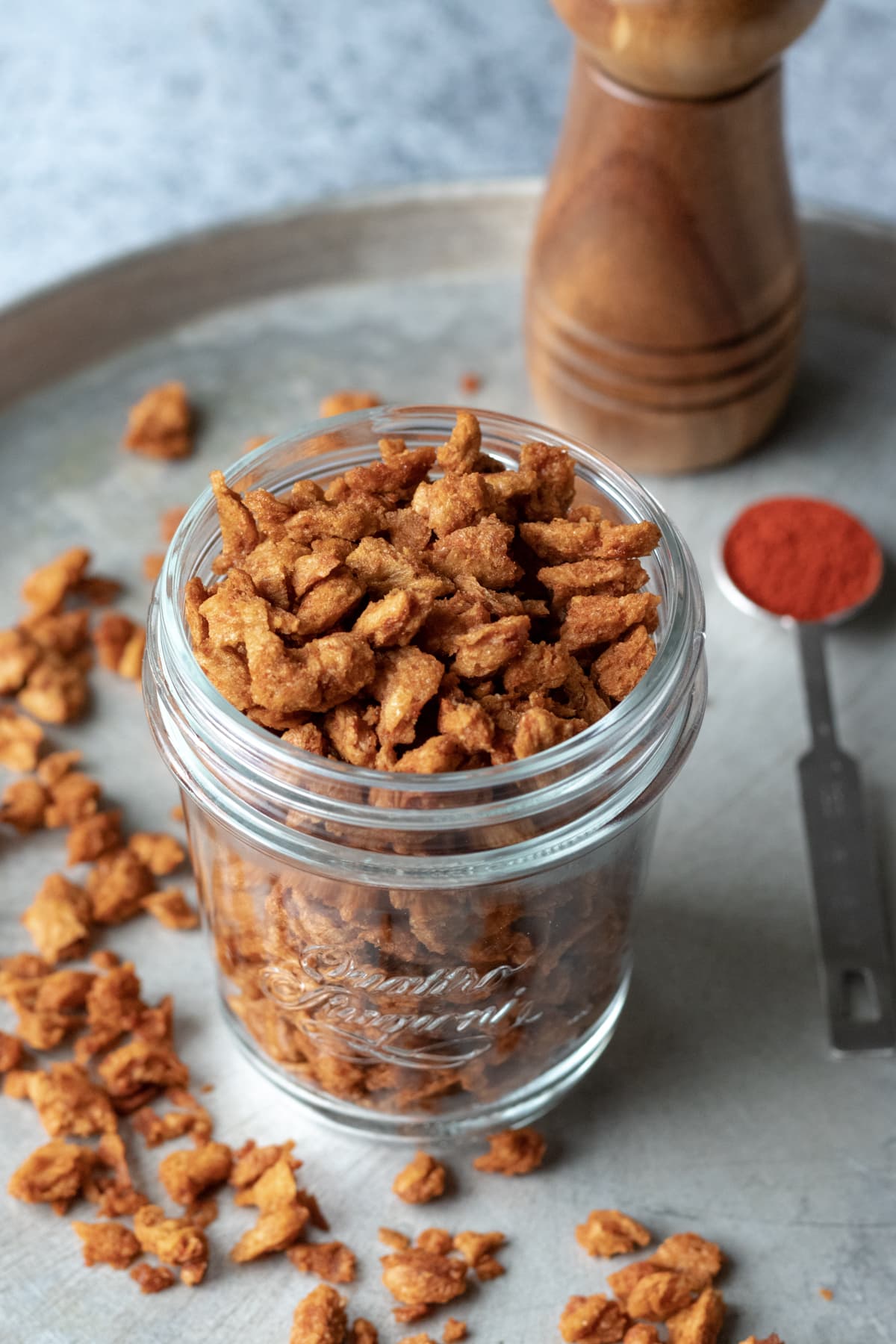 chunky vegan bacon bits in a jar and scattered on a tray.