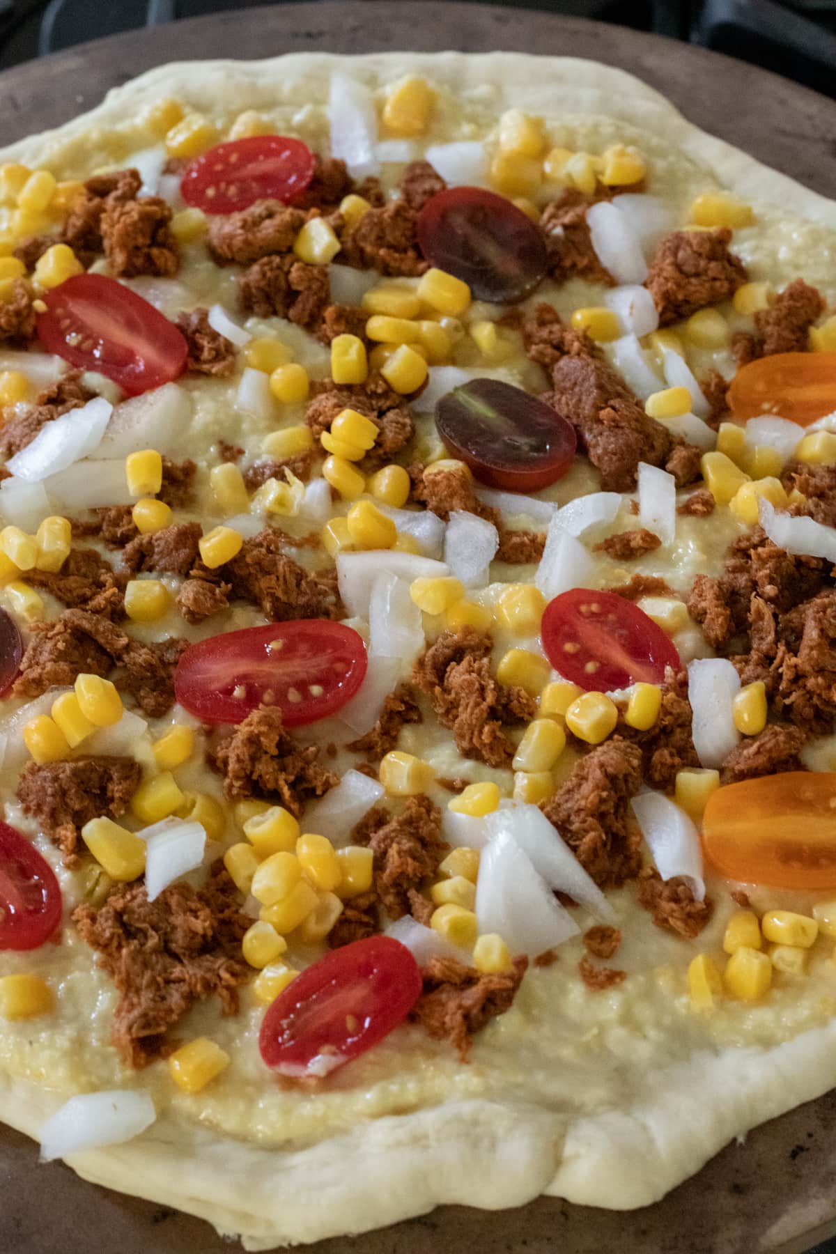 adding ingredients to rolled out pizza dough.