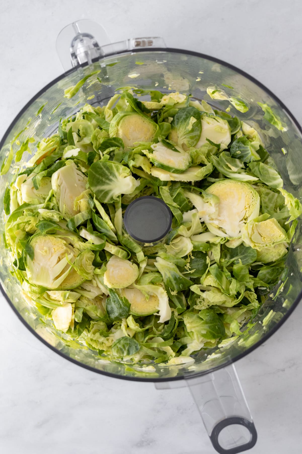 looking at sliced brussels in the bowl of a food processor.