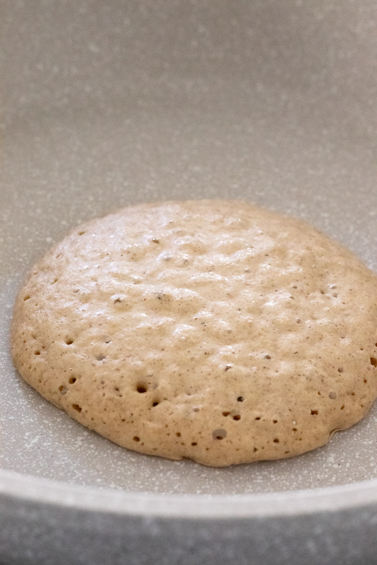 cooking a pancake in a non-stick skillet with brown edges and bubbles on top.