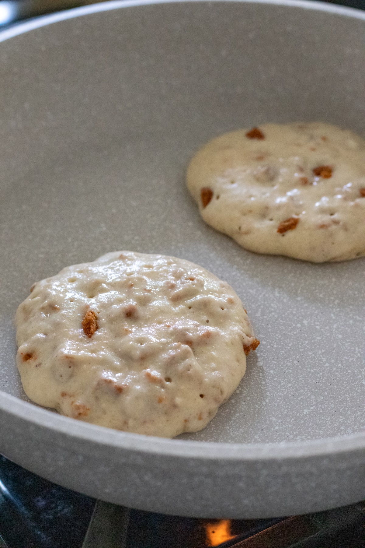 two pancakes cooking in a non-stick pan