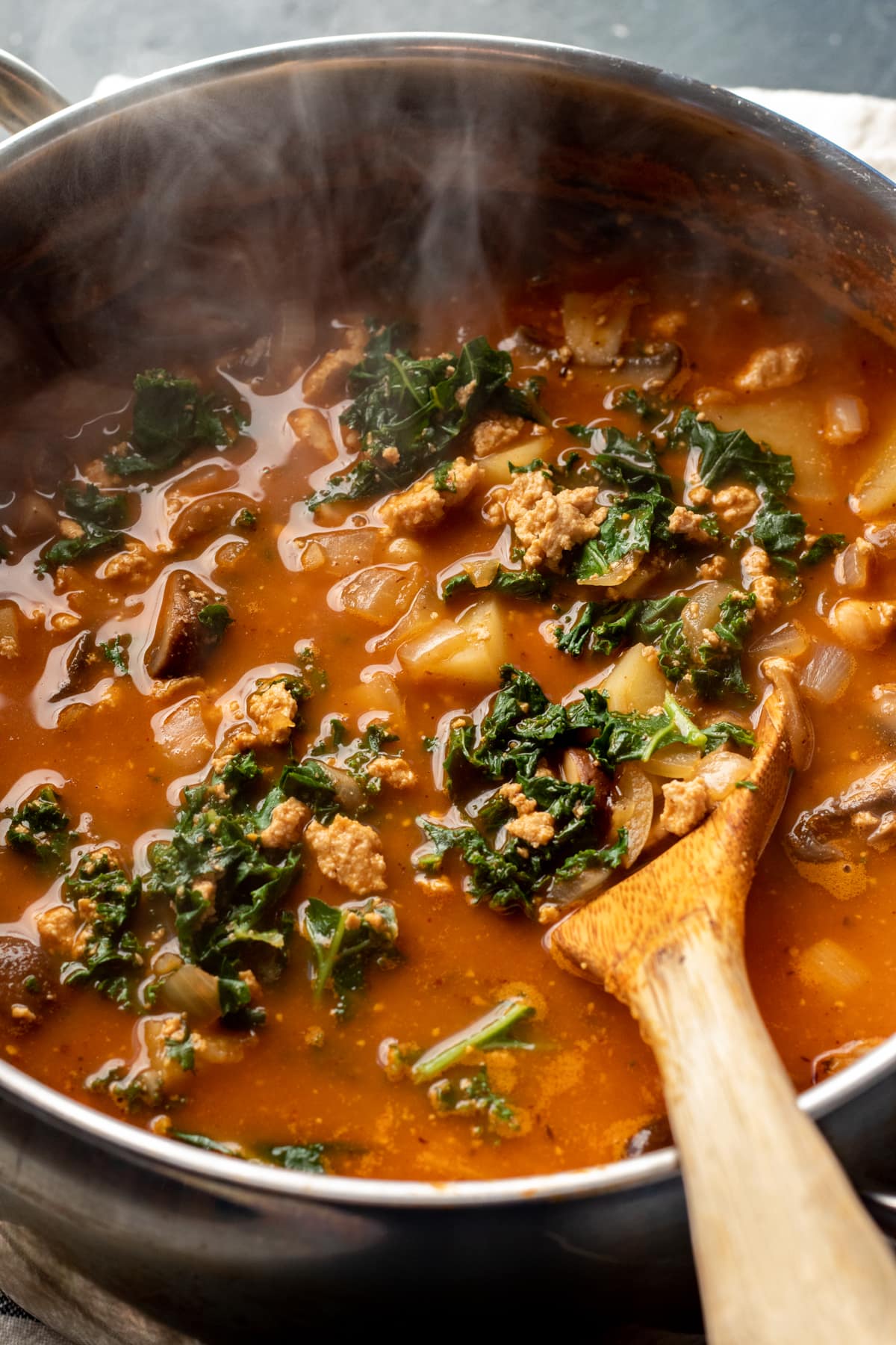 steaming hot pot of vegan soup with potatoes and kale.