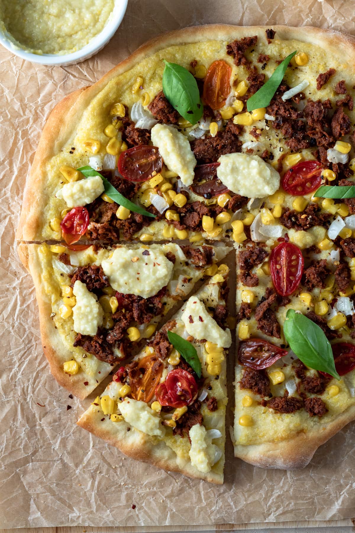 colorful vegan chorizo and corn pizza on a cutting board.