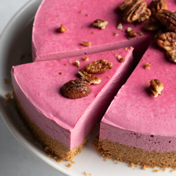 close up of pink cheesecake topped with candied pecans