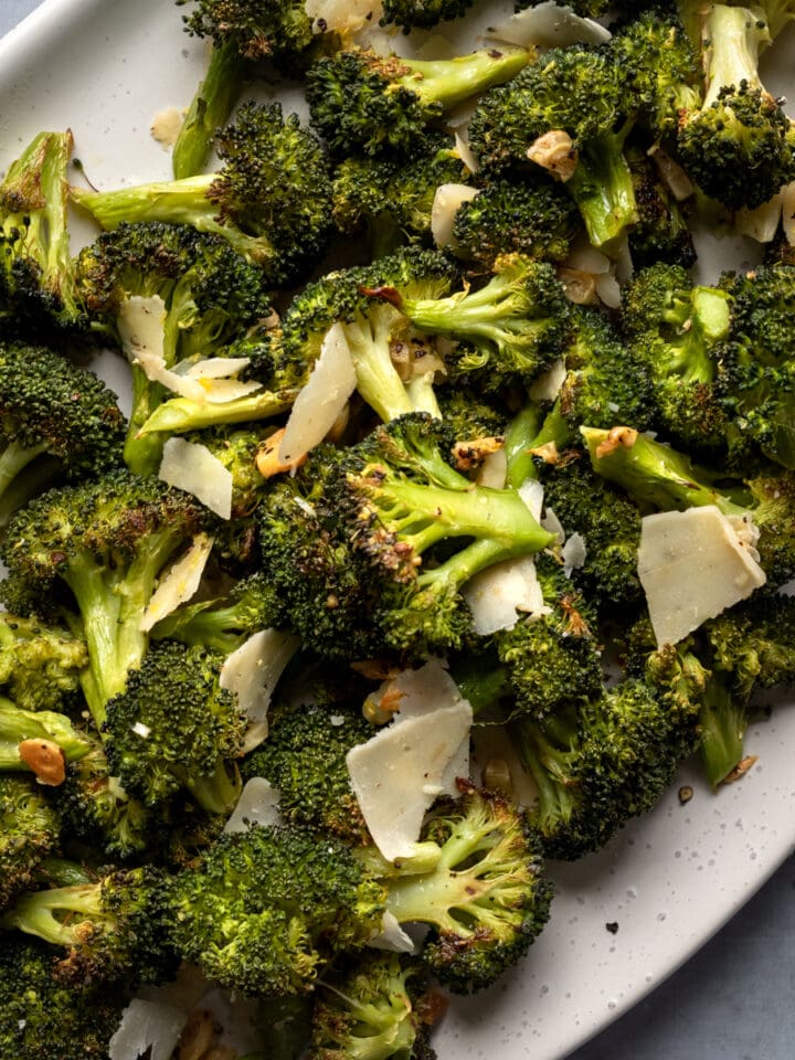 roasted broccoli on a serving platter tossed with vegan parmesan