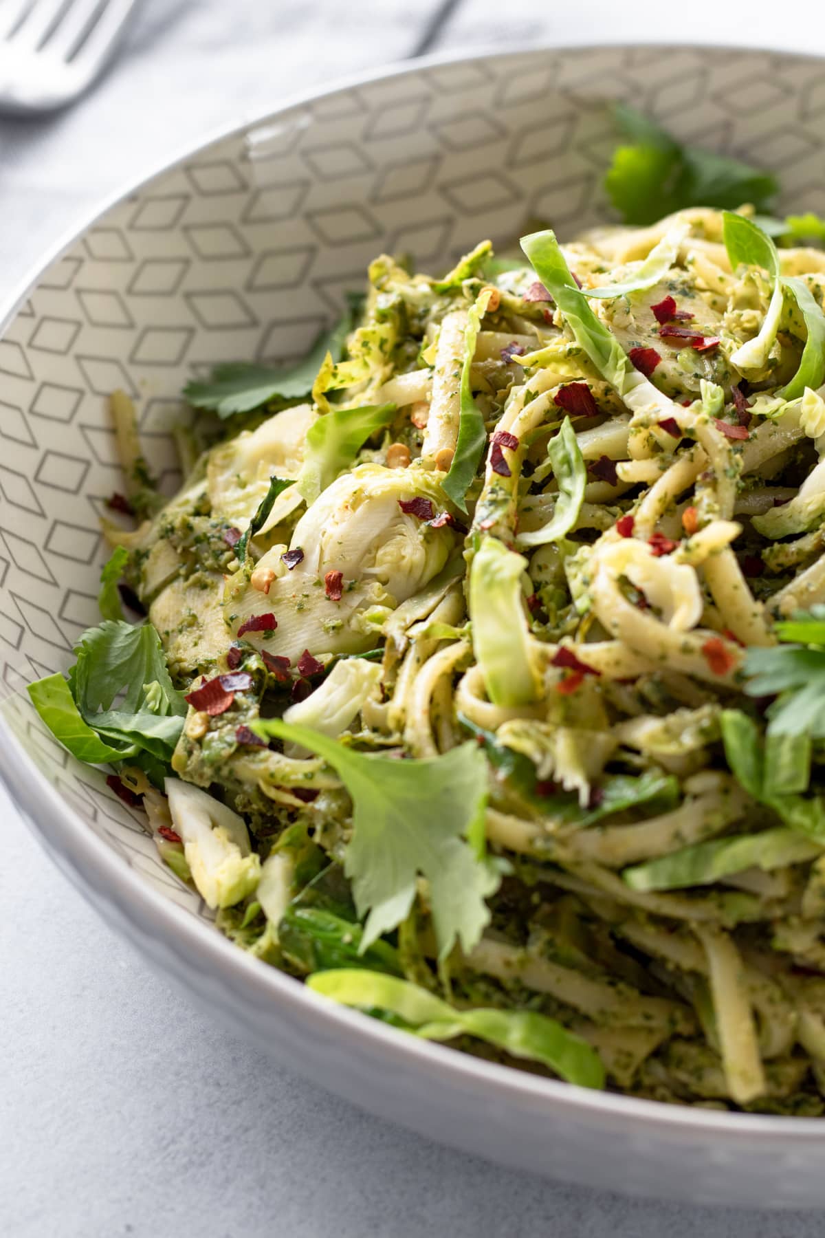 backlit photo of zhoug pasta in a large serving bowl.