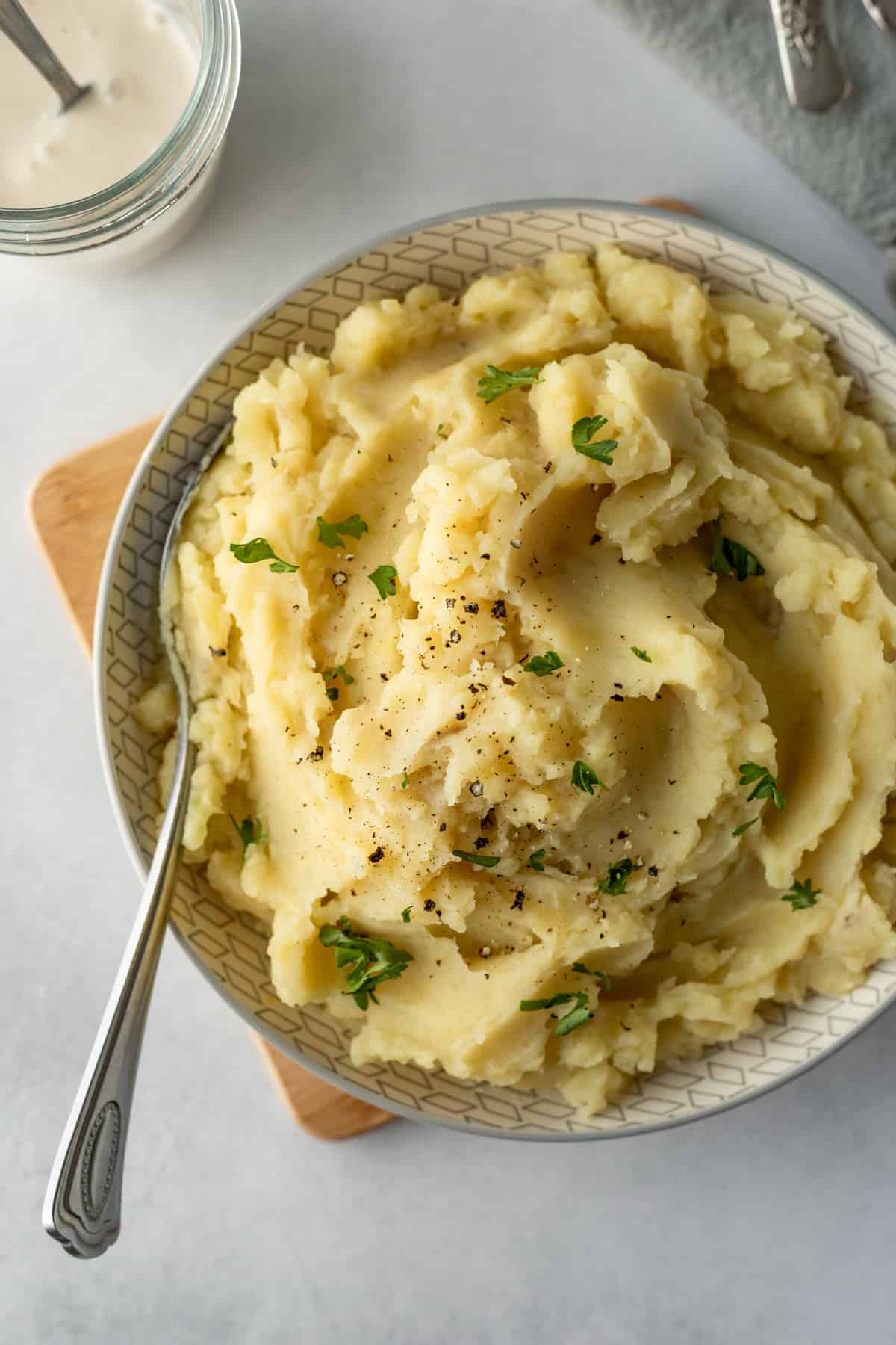 creamy potatoes in a bowl with yogurt in background.
