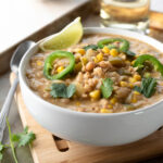 close up of white chili in a bowl topped with lime wedge and jalapeño