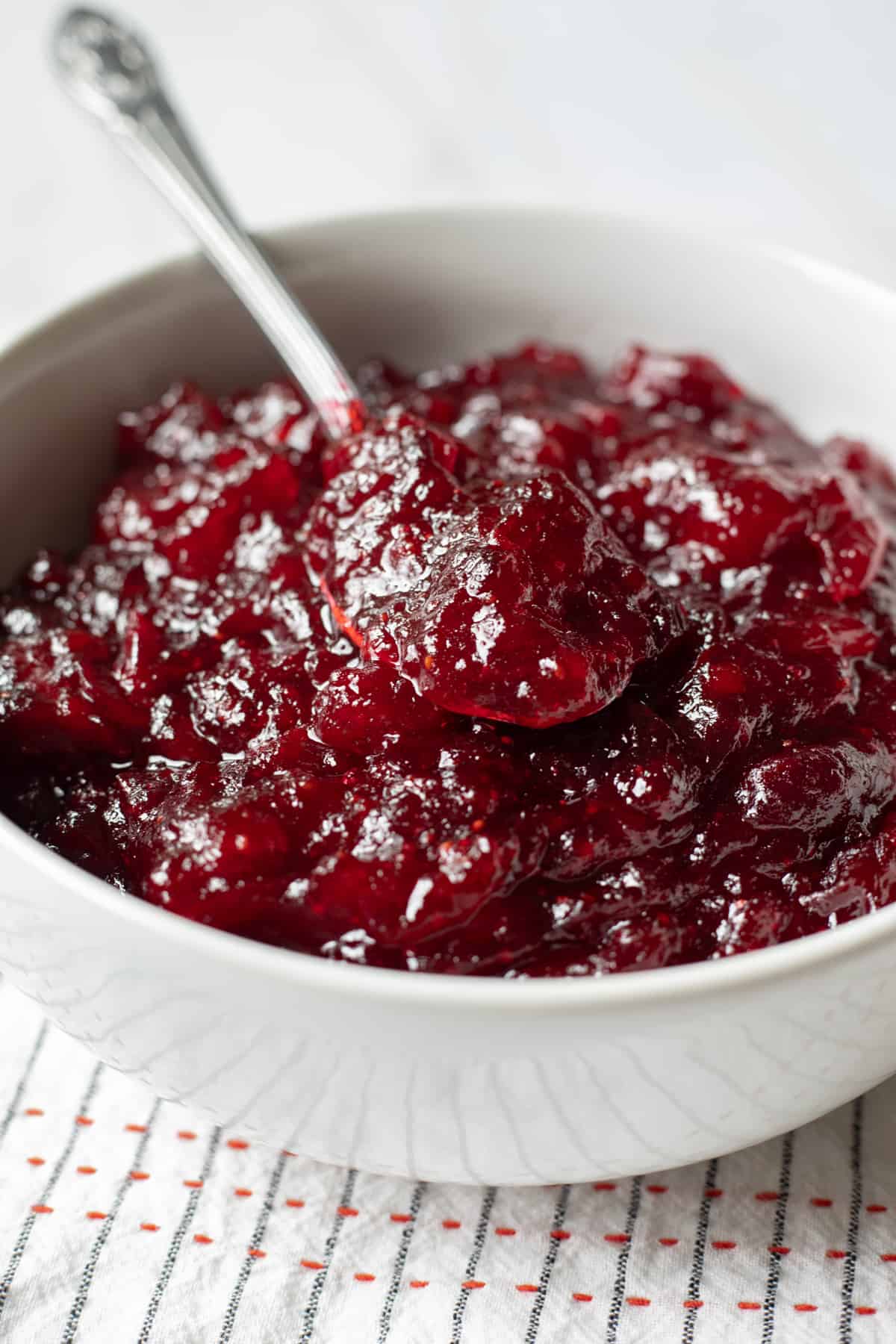 close up of deep red cranberry sauce in a white bowl.