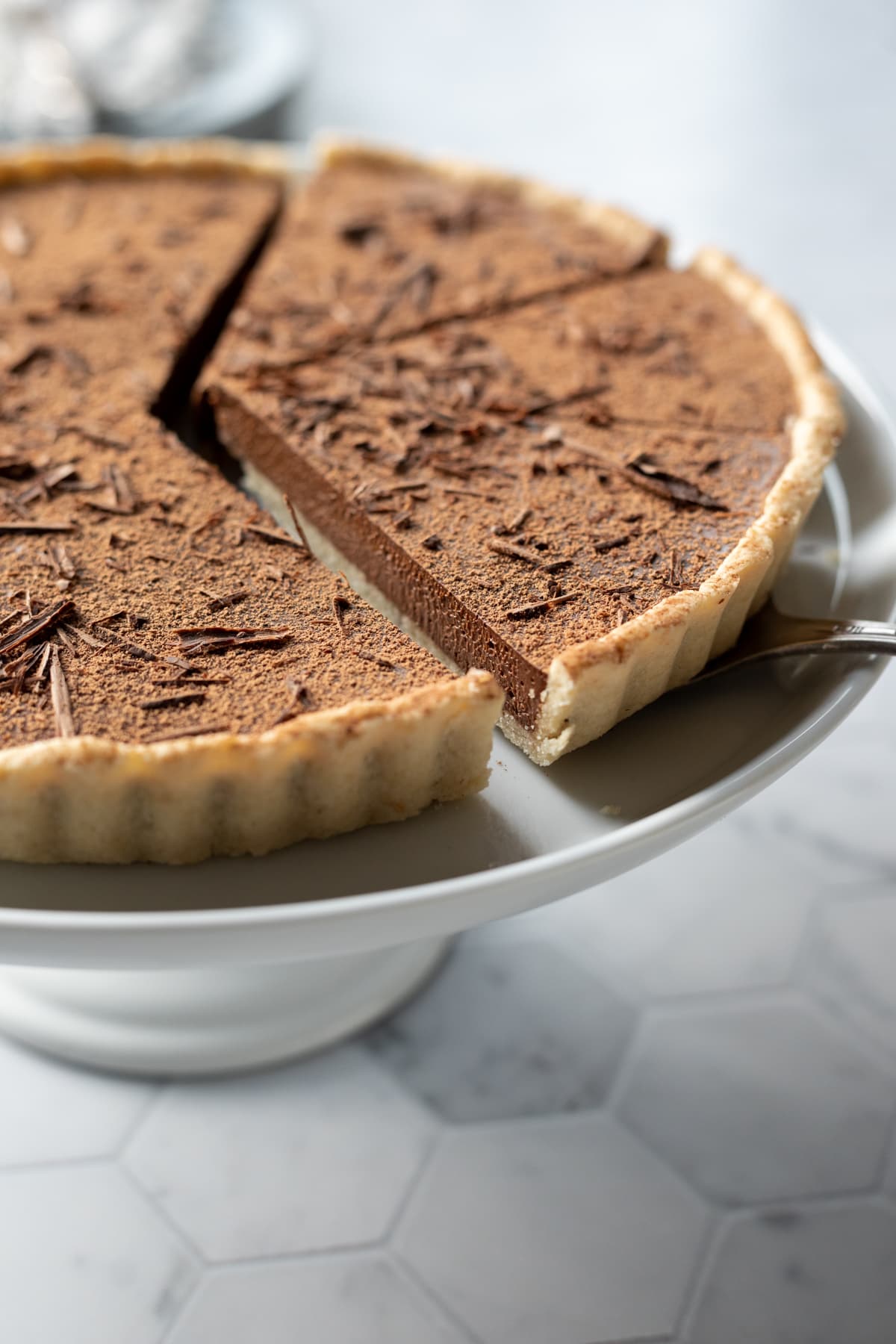 close-up of tart on cake stand with slices cut to show creamy texture of filling.