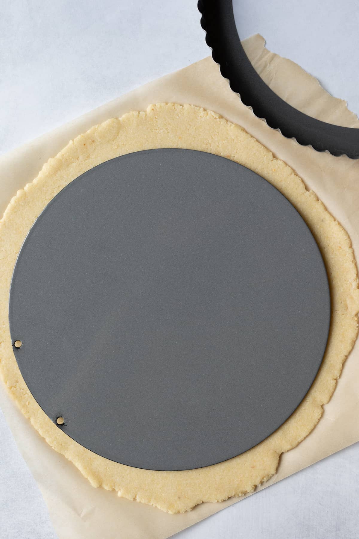 removable bottom of tart pan lying on rolled out dough, ready to flip