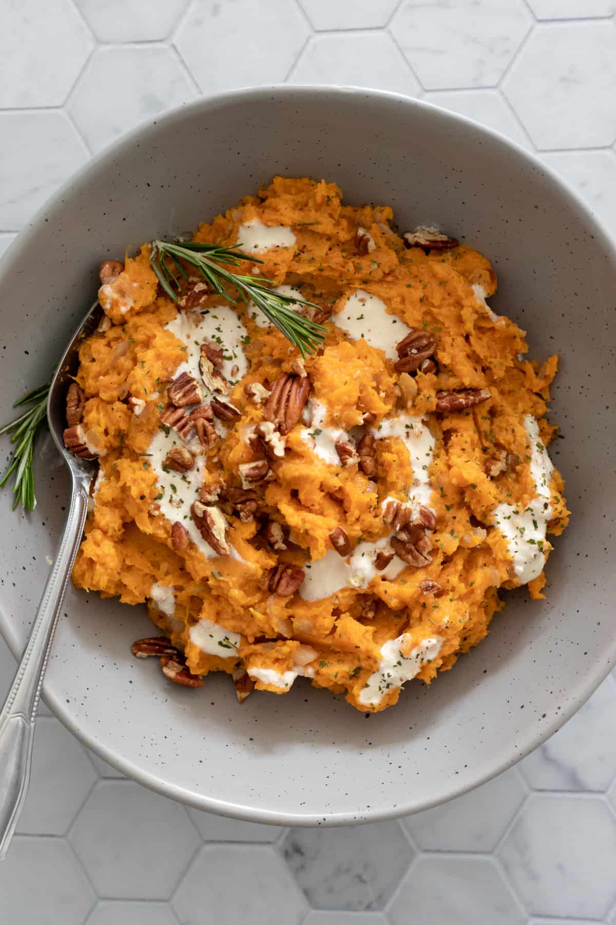 colorful sweet potato mash in a bowl swirled with yogurt and pecans.