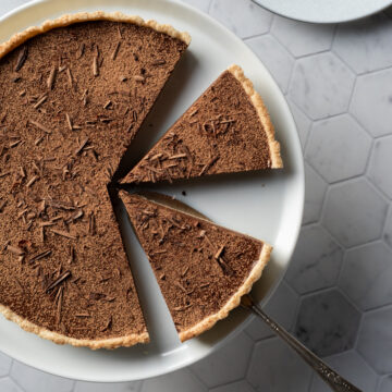 top view of chocolate tart on white plate with slices cut