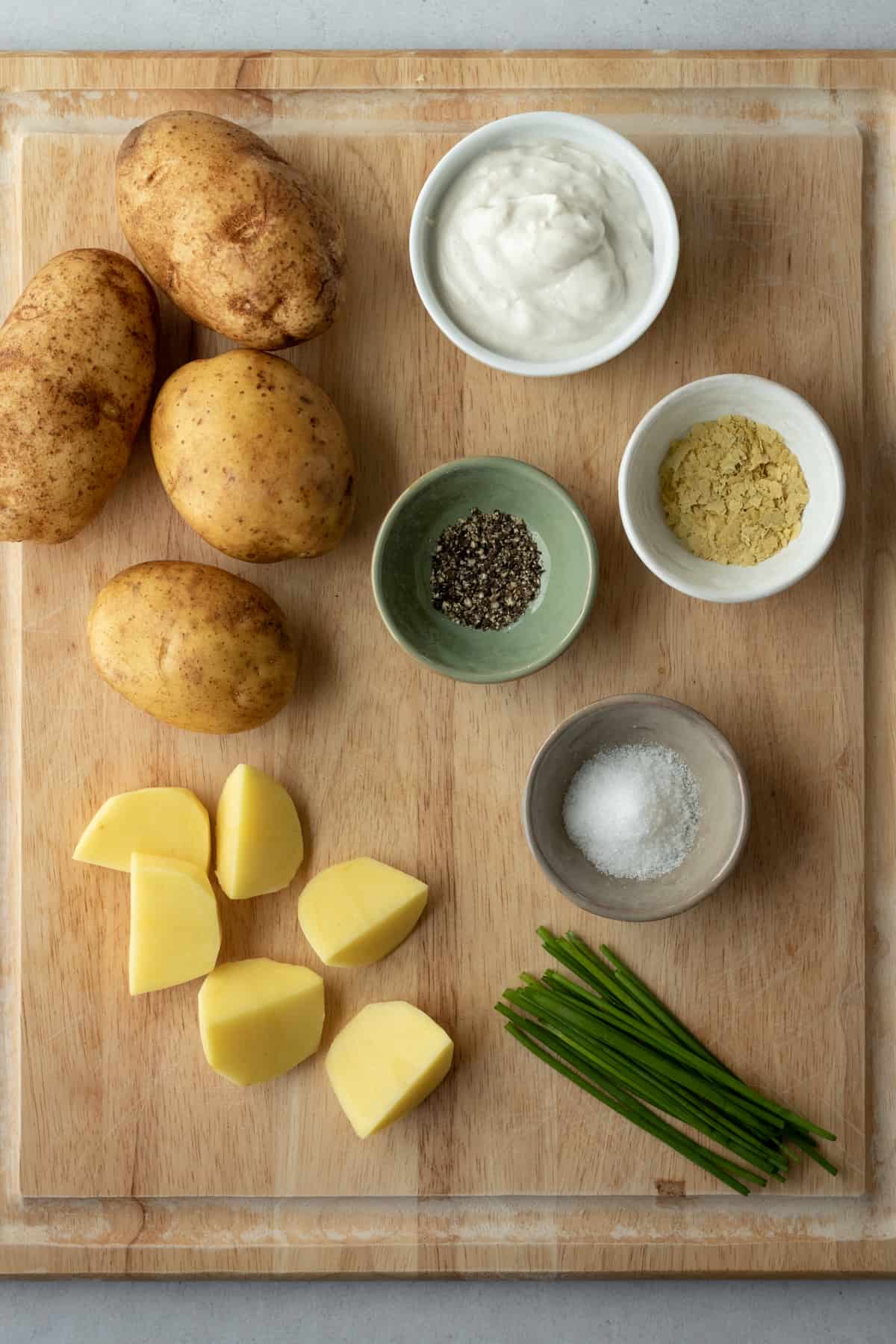 Ingredients for mashed potatoes on a cutting board.