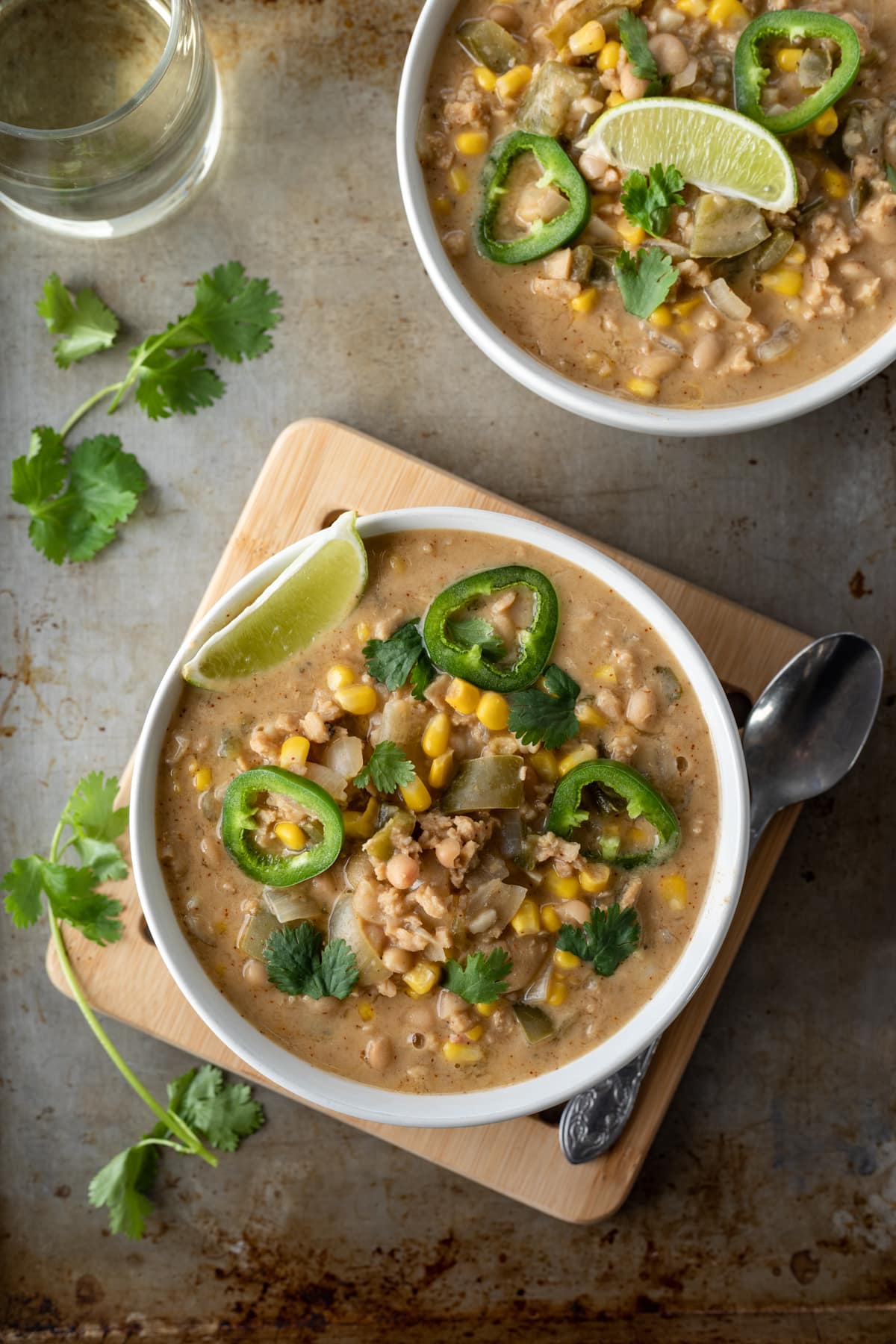 two bowls of white bean chili with garnishes.