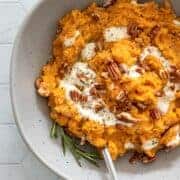 creamy sweet potato mash in a bowl with pecans and vegan yogurt.