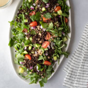 A colorful black lentil salad on a white platter.
