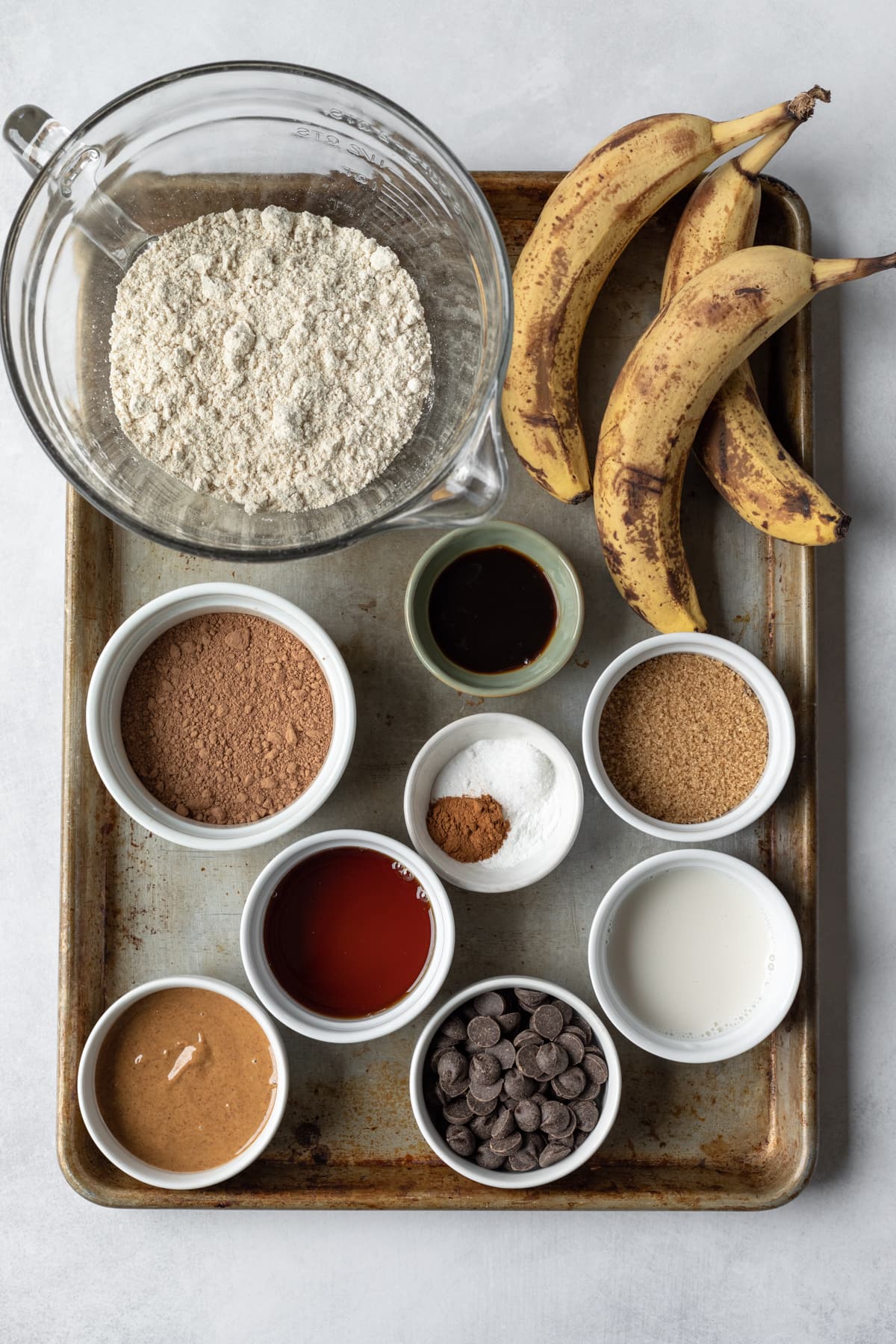 Ingredients for chocolate banana bread spread out on a large baking sheet.