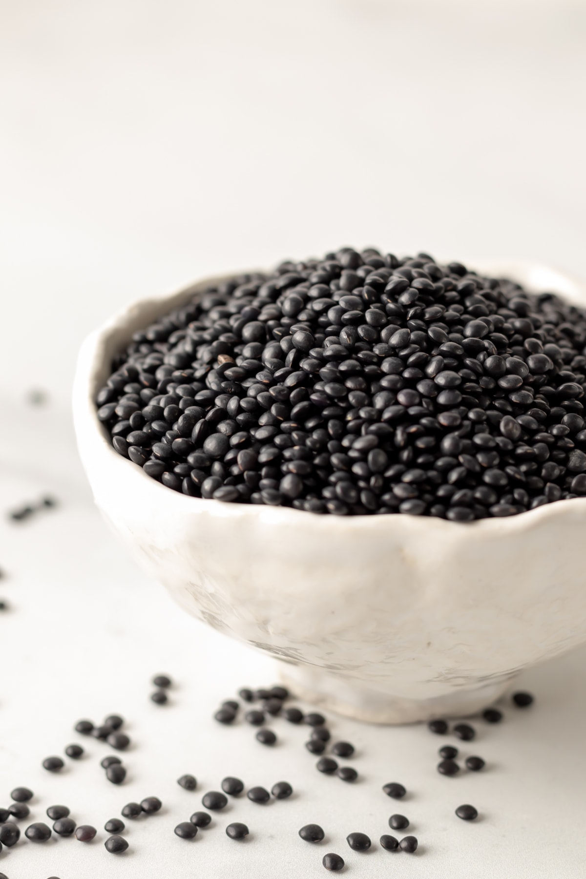 small white bowl filled with uncooked black lentils