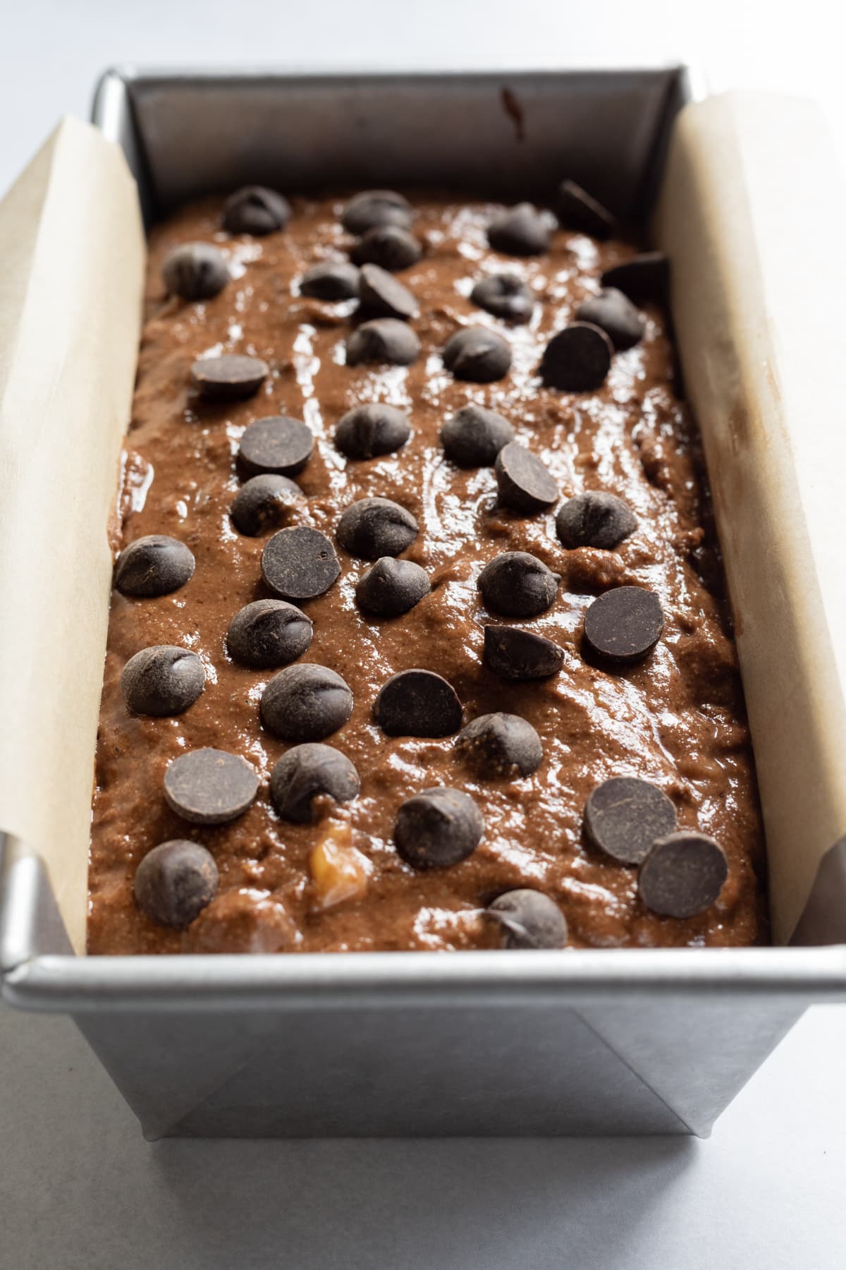 batter in a loaf pan topped with chocolate chips.